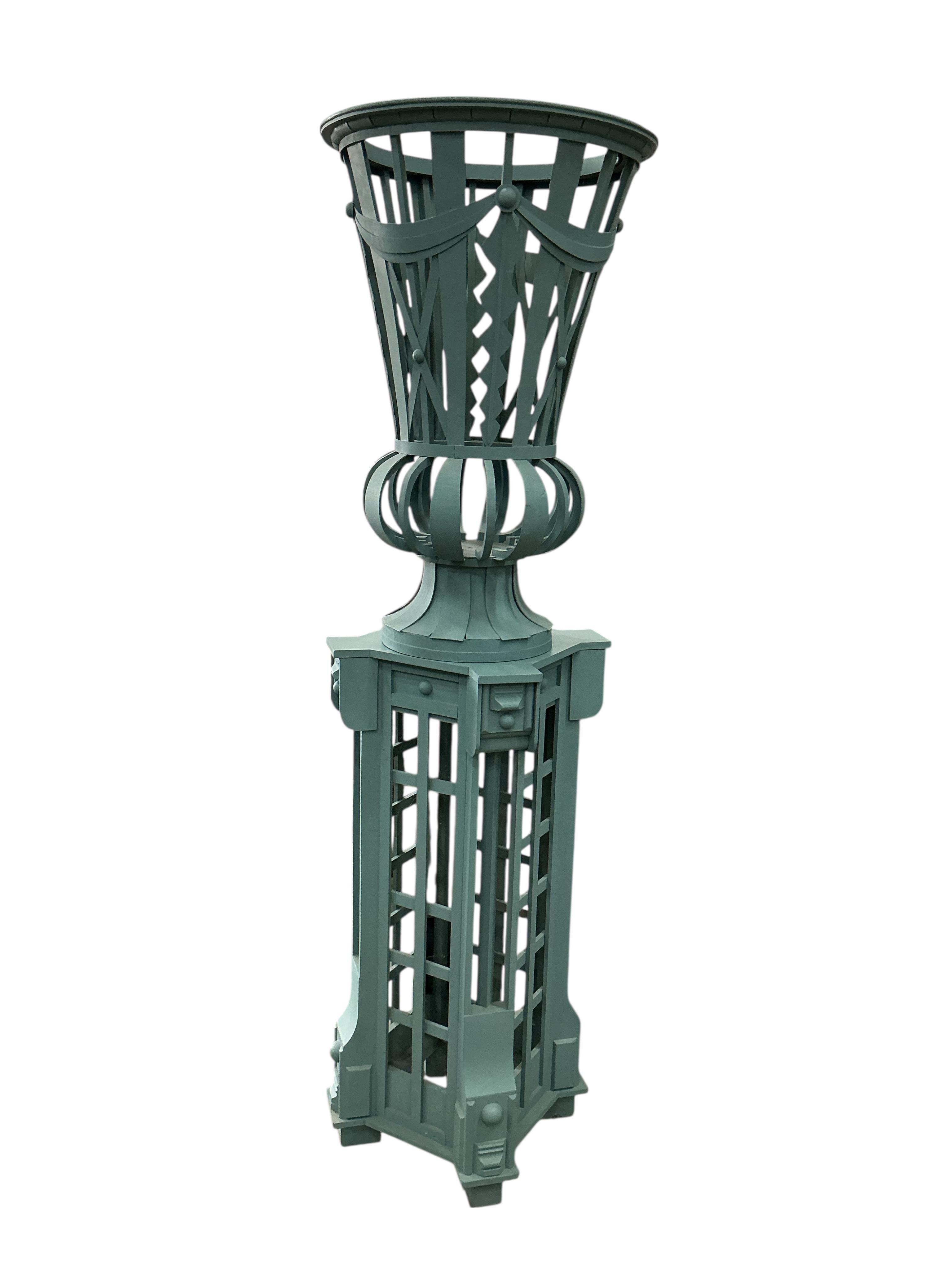 A green painted wood urn and pedestal, height 175cm, Provenance: The late Kenneth Turner (1936-2025), celebrity florist, designer and perfume retailer, he received the Royal Warrant from the Prince of Wales in the 1990s
